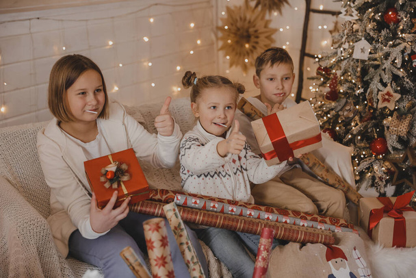 Χαριτωμένα παιδιά που τυλίγουν χριστουγεννιάτικα δώρα. Συσκευασία δώρου. Οικογένεια, χειμερινές διακοπές και οι άνθρωποι έννοια - Φωτογραφία, εικόνα