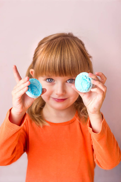 Mooi klein meisje met een blauw zoet dessert macarons in haar handen portret close-up, zoete gebak gelukkige kinderlijke emoties, selectieve focus - Foto, afbeelding