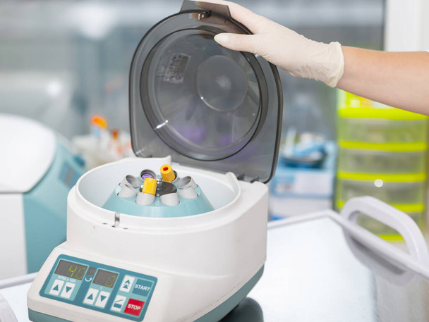 Medische centrifuge. Wetenschapper die een monster in een centrifugemachine laadt in een medisch of wetenschappelijk laboratorium - Foto, afbeelding