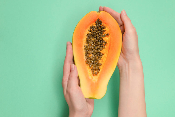 Frutto di papaya su uno sfondo verde in mani di donna. Frutta tropicale. Mezza papaia.  - Foto, immagini