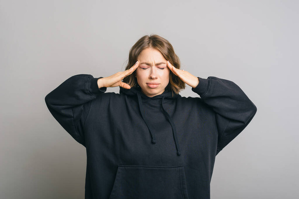 Photo d'une jeune femme ayant une migraine et debout sur un fond gris. - Photo, image