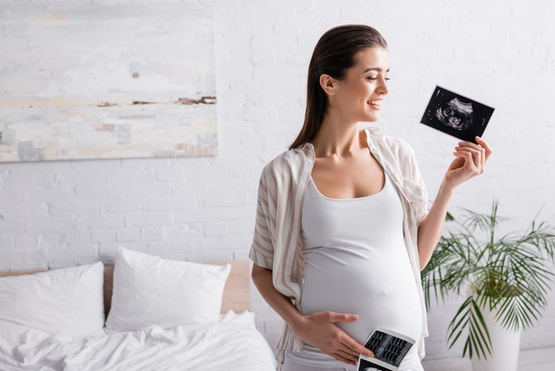 sorrindo e mulher grávida segurando exames de ultra-som  - Foto, Imagem