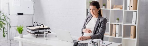 happy pregnant businesswoman looking at laptop in office, banner - Fotografie, Obrázek