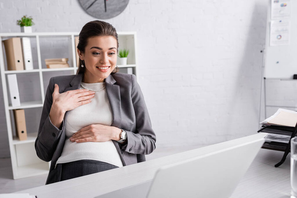 happy pregnant businesswoman smiling during video call  - Foto, afbeelding