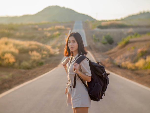 A woman with a backpack standing in the middle of the road - Foto, imagen