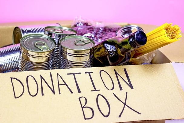 Коробка для пожертвований с едой (макароны, банки, овощи и др.). Добровольчество и социальная помощь, концепция благотворительности. - Фото, изображение