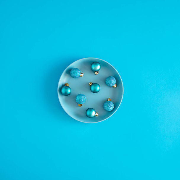 Blue Christmas baubles on pastel blue plate. Minimal surrealism New Year dinner concept. - Foto, immagini