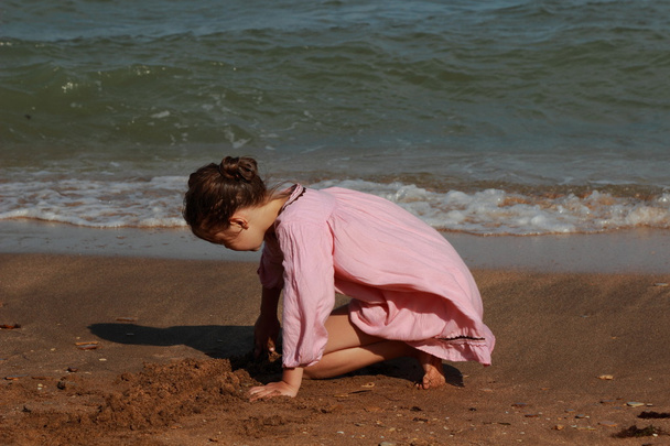 Outdoor image of beautiful little girl playing over sea beach, East Crimea - Foto, Imagem