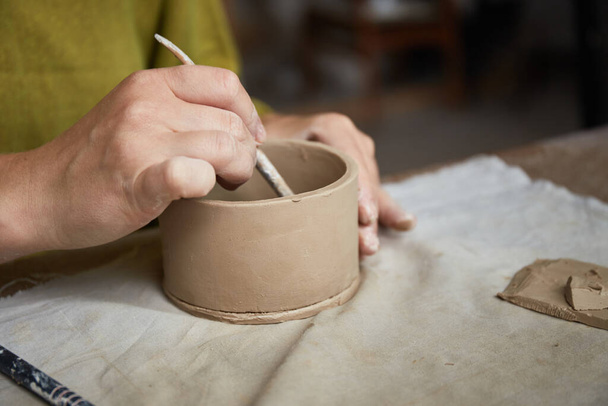 Γυναίκα κεραμίστρια που δουλεύει σε στούντιο κεραμικής. Χέρια Κεραμικού Βρώμικο του Κλέι. Διαδικασία δημιουργίας κεραμικής. Η Master ceramist εργάζεται στο στούντιο της - Φωτογραφία, εικόνα