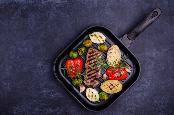 Fried beef steak with vegetables. Stone background. Top view.  - Foto, afbeelding