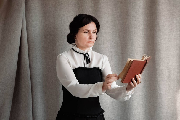 Woman in vintage style dressed holding a book in his hands on a background of linen cloth. - Foto, Imagen
