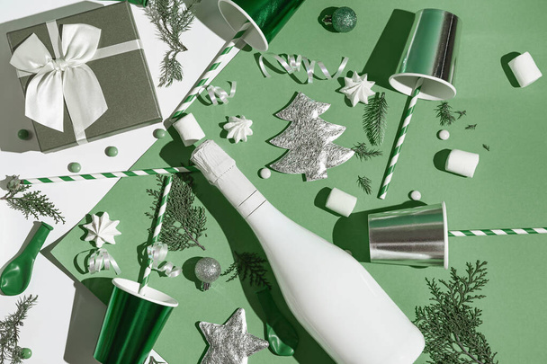 Christmas composition made of paper glasses with straws, present box, white champagne bottle, meringues and green baubles. Festive and party concept. 2022 new year background.Top view. Flat lay - Фото, зображення