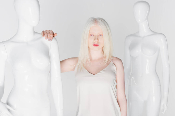 Hezké blondýny a albíny žena stojící v blízkosti figurín izolované na bílém  - Fotografie, Obrázek