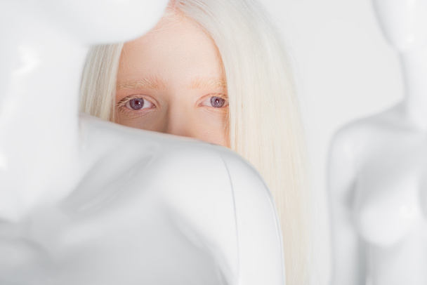 Albino kadın beyaz mankenin yakınındaki kameraya bakıyor.  - Fotoğraf, Görsel