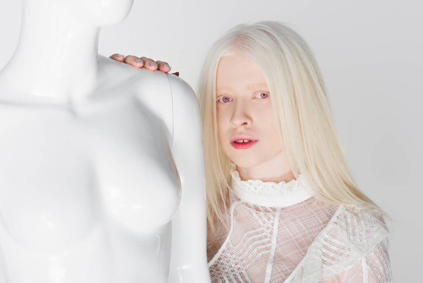 Blonde woman in blouse looking at camera near mannequin isolated on white  - Fotoğraf, Görsel