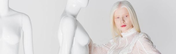 Блондинка в стильной блузке, стоящей рядом с манекенами изолированы на белом, баннер  - Фото, изображение
