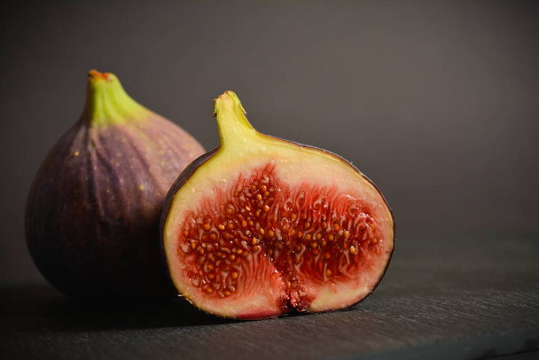 Close up of Azerbaijani fig fruit. Exotic eastern fruit. Segmented berry isolated on black stone background. Copy space image. Text space for banner - Foto, afbeelding