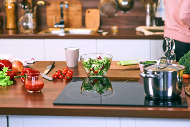 Процесс приготовления на кухне - кастрюля, овощи на столе. - Фото, изображение