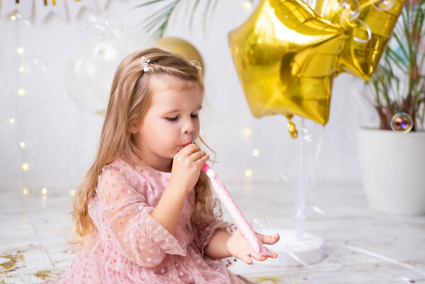 heureuse fille enfant avec les cheveux longs en robe rose siffler et célébrer son anniversaire - Photo, image