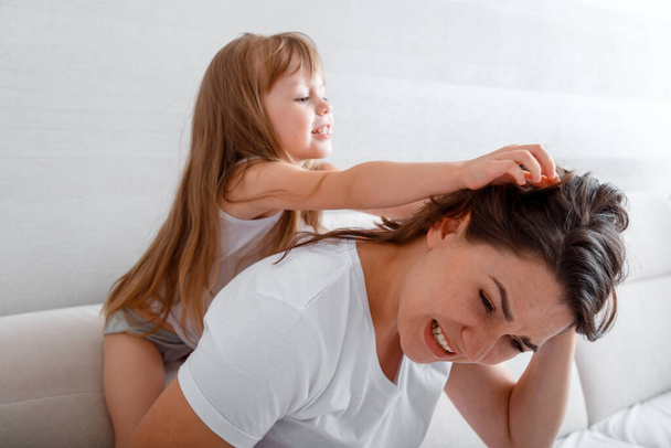 Naughty little girl pulls moms hair at home. Fight quarrel childrens whims bad relationship between daughter and mother. Complex nature of the child - Foto, Bild