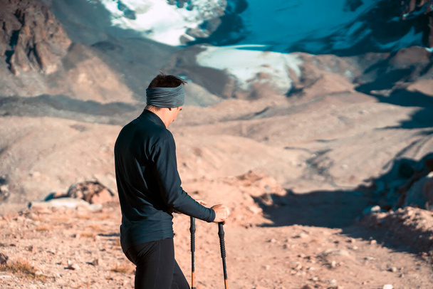 Traveler with trekking poles is walking in the snowy mountains. - Photo, Image
