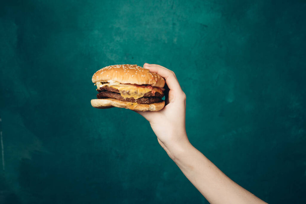 hamburger in hands close-up fast food green background - Фото, изображение