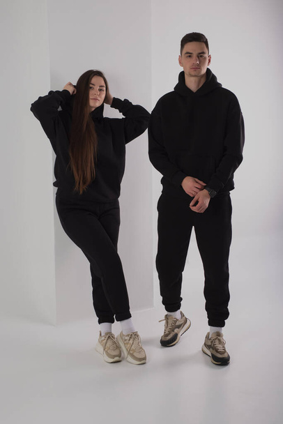 Couple posing in studio wearing black hoodie costumes - Фото, зображення