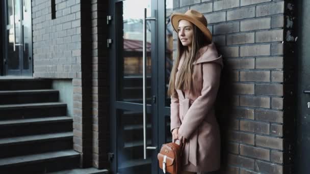 Ritratto di giovane donna in cappotto e cappello dello sfondo dell'edificio per uffici - Filmati, video