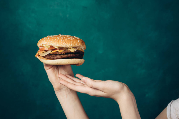 hamburger in hands close-up fast food green background - Foto, afbeelding