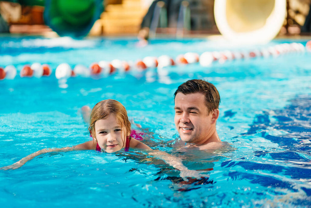 dad teaches his daughter to swim in the pool. swimming training.  - Фото, изображение