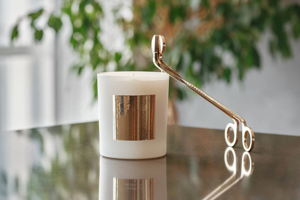 Goldene Trimmer-Kerze mit Schere und Wachskerze auf dem Tisch im Wohnzimmer - Foto, Bild