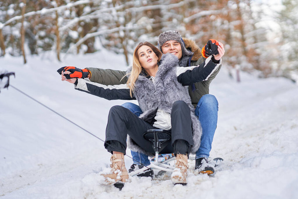 Пара веселится с санями на снегу зимой - Фото, изображение