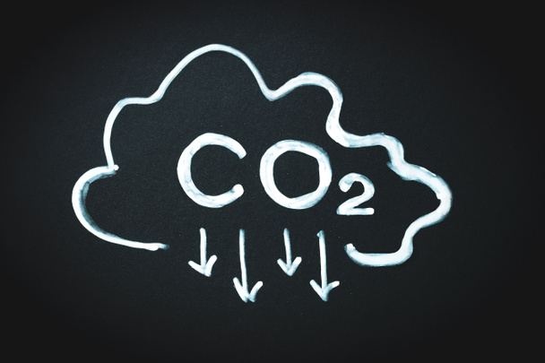 Szén-dioxid jel és nyíl lefelé mutat, és felhő a fekete táblán. A szén-dioxid-kibocsátás csökkentése, a globális felmelegedés és az éghajlatváltozás koncepciójának korlátozása - Fotó, kép