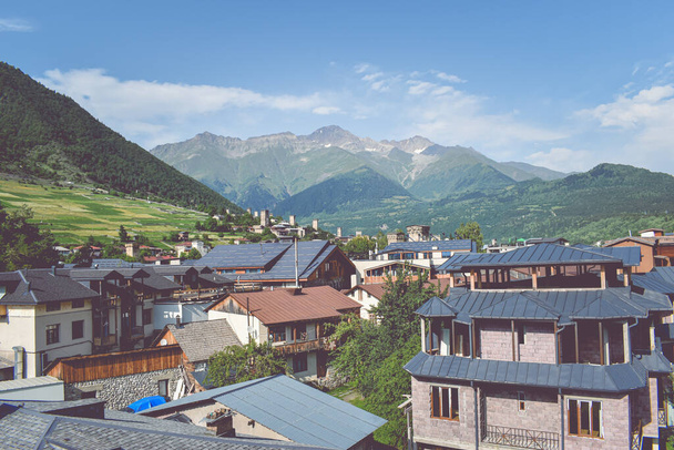 Beautiful highland townlet Mestia in the Svaneti region, Georgia, Asia. Cityscape view of traditional rural houses with green hills, famous towers and mountains in the background - Photo, image