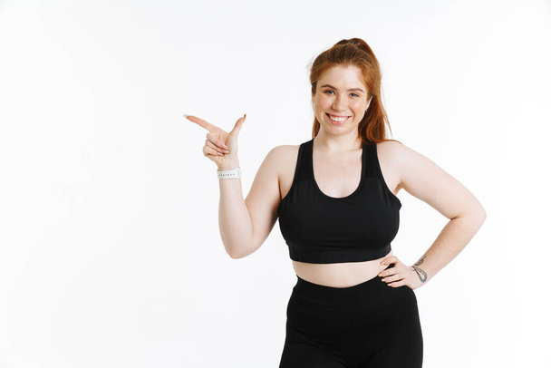 Young ginger woman smiling while pointing finger aside isolated over white background - Photo, Image
