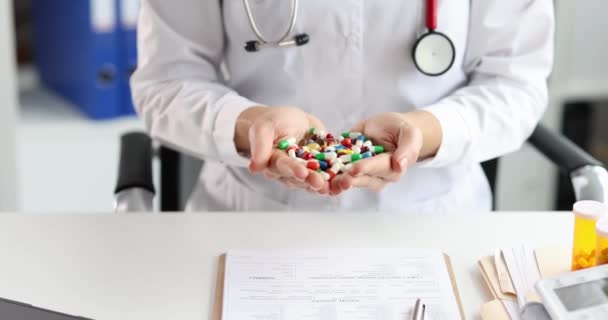 Doctor vrouw met een handvol veelkleurige capsules met geneesmiddelen in kliniek 4k film slow motion - Video