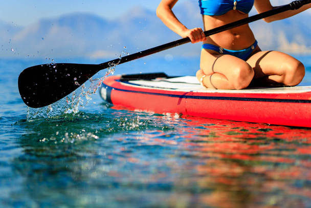 Woman sitting on sup board and enjoying peace and quiet outdoors - Foto, imagen