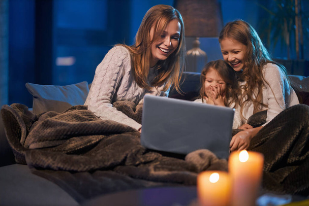 Mother with daughters watching funny videos on laptop  - Фото, зображення