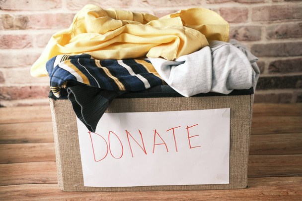 Donation box with donation clothes on a wooden table . - Фото, изображение