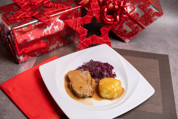 Geroosterd varkensvlees met aardappelknoedels en rode kool. Zelfgemaakt eten, kerstdiner  - Foto, afbeelding