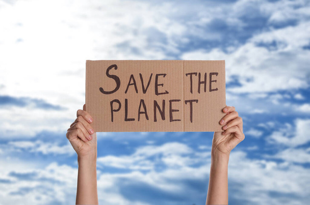 Protestor holding placard with text Save The Planet against blue sky, closeup. Climate strike - Фото, зображення