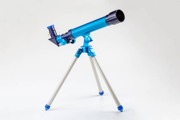 三脚に青いおもちゃの望遠鏡、白い背景に孤立した単一のオブジェクト。驚くべき、宇宙観測科学機器、若い子供のためのツール、子供、天文学趣味の概念記号、誰も - 写真・画像