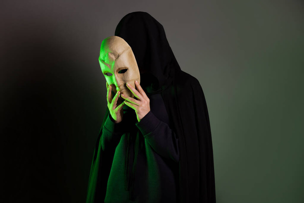 An anonymous villain, a hidden figure in a black cape with a hood. A mystical character - Фото, зображення