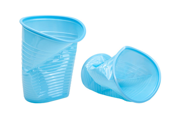 Tazas de plástico vacías azules aplastadas, dañadas, desechadas, objetos aislados sobre fondo blanco, recortados. Taza de bebidas plásticas usada basura, tirar vasos de agua plásticos usados, basura, concepto de basura - Foto, imagen