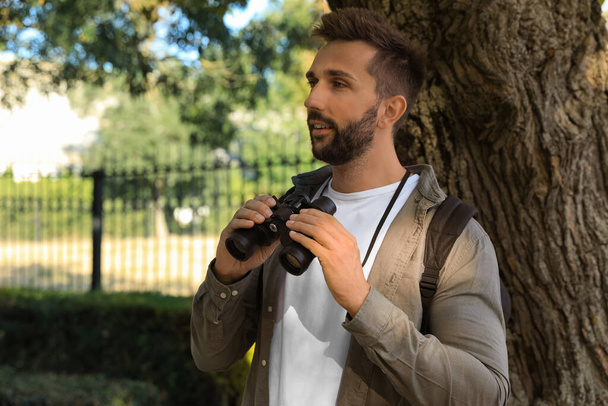Handsome man with binoculars spending time in nature reserve - Zdjęcie, obraz
