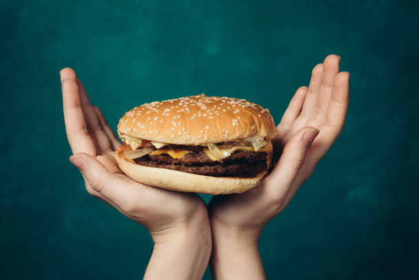 hamburger in hands close-up fast food green background - 写真・画像