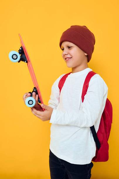 щасливий школяр з червоним рюкзаком червоний скейтборд концепція способу життя дитинства
 - Фото, зображення