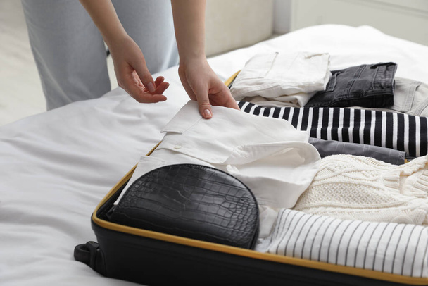 Woman packing suitcase for trip in bedroom, closeup - Fotoğraf, Görsel