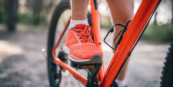 Legs of man in sneakers riding bicycle - Foto, Bild
