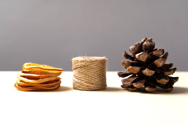 Stone pine cone (Pinus pinea), dried tangerine slices and a skein of string. Side view. Christmas concept.  - Photo, Image
